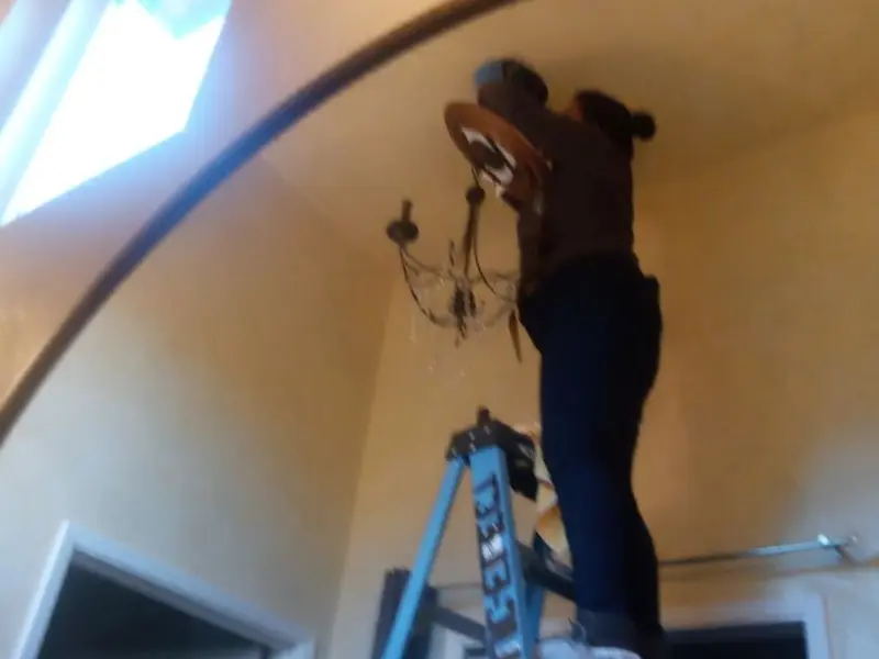 Electrician installing a chandelier in a Mount Washington residence